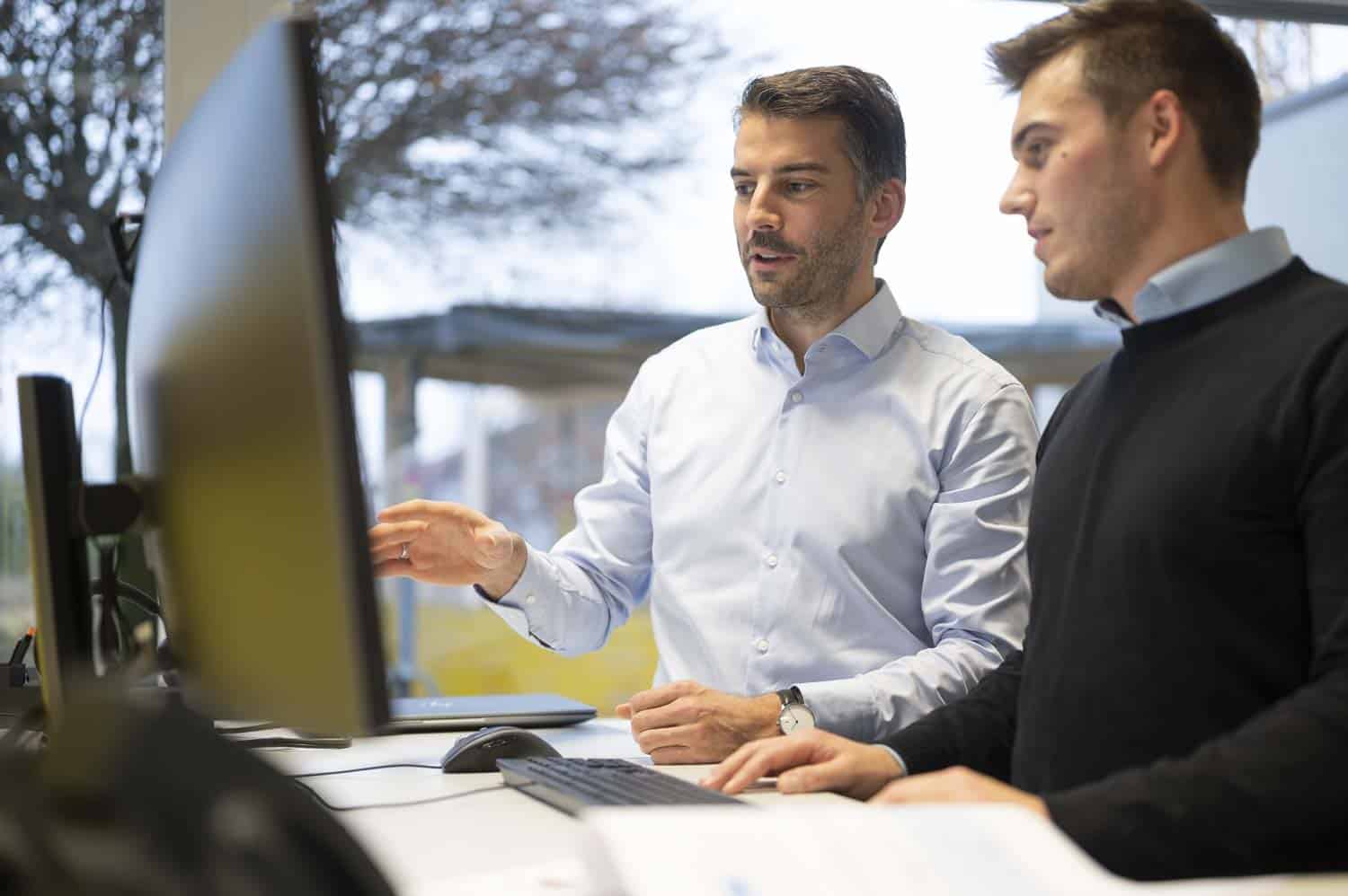 Teammitglieder bearbeiten technische Daten am Computer