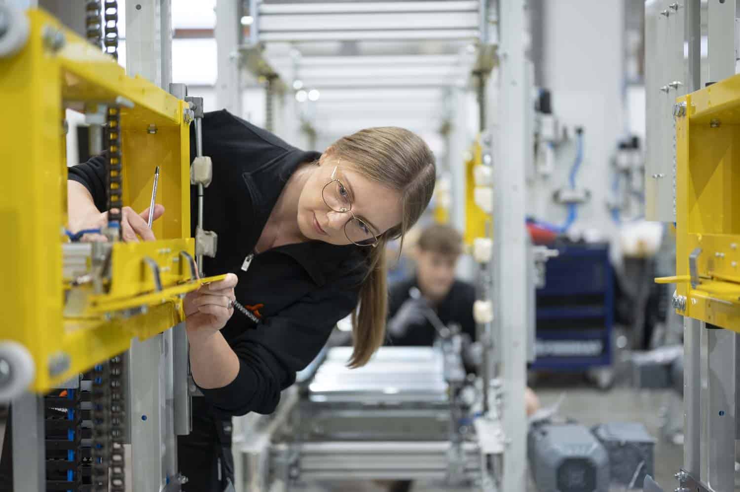 Mitarbeiterin prüft Maschine in der Fertigungshalle